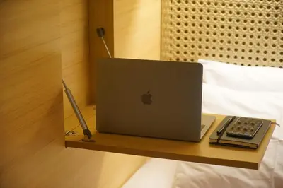 an apple laptop sitting on a wooden shelf on a bed at Borough Capsule Hostel Bali in Legian