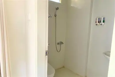 a bathroom with a shower with a toilet and a sink at The Yani Hotel Bali in Denpasar
