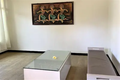a table in a room with a painting on the wall at The Yani Hotel Bali in Denpasar