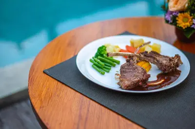 a plate of meat and vegetables on a table at Ziva a Boutique Villa in Seminyak