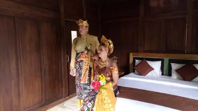 a man and a woman wearing a crown standing next to a bed at The Garden Villa in Sanur