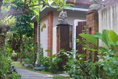 a garden with a statue in front of a house at The Garden Villa in Sanur