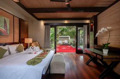 a bedroom with a bed and a desk and a table at Le Jardin Villas Seminyak in Seminyak