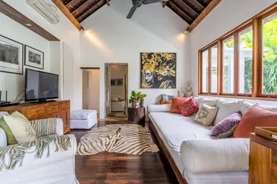 a living room with a white couch and a tv at Baby Melon Villas in Seminyak