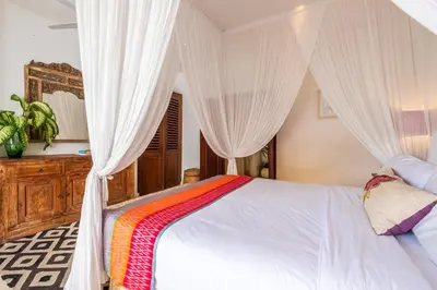 a bedroom with a bed with white curtains at Baby Melon Villas in Seminyak