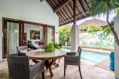 a dining room with a table and chairs and a pool at Baby Melon Villas in Seminyak