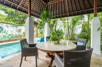 a dining room with a table and chairs and a pool at Baby Melon Villas in Seminyak