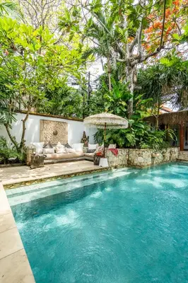 a swimming pool in front of a house with trees at Baby Melon Villas in Seminyak