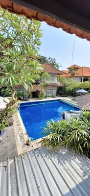 a blue swimming pool in front of a house at The Taman Ayu Seminyak 10 Minute walking to the BEACH in Seminyak