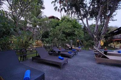a row of chairs and tables in a park with trees at The Taman Ayu Seminyak 10 Minute walking to the BEACH in Seminyak
