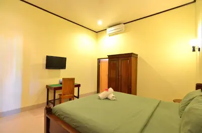a bedroom with a bed with a tv and a chair at Arik Homestay Canggu in Canggu