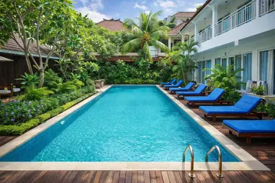 a pool at a hotel with blue chairs and trees at Easy Surf Camp in Kuta