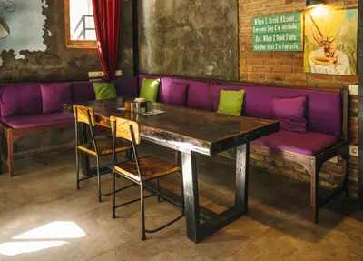 a table with chairs and a purple couch in a restaurant at Easy Surf Camp in Kuta