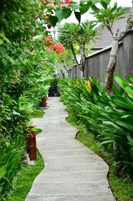 a walkway in a garden with flowers and trees at The Khayangan Dreams Villa, Seminyak in Seminyak