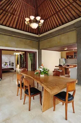a dining room with a large wooden table and chairs at Bali Aroma Exclusive Villas in Seminyak