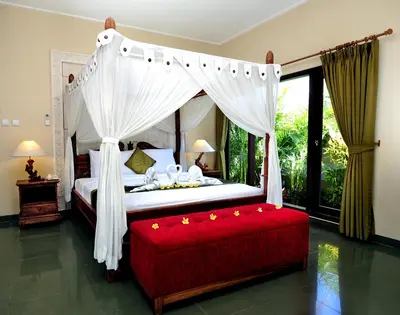 a bedroom with a canopy bed and a red bench at Bali Aroma Exclusive Villas in Seminyak
