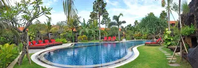 a swimming pool with red chairs in a yard at Bali Aroma Exclusive Villas in Seminyak