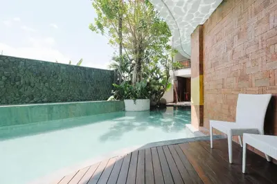 an infinity pool in a house with two chairs at djabu Seminyak Hotel in Seminyak
