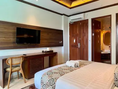 a bedroom with a bed and a desk and a tv at djabu Seminyak Hotel in Seminyak