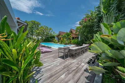 a wooden deck with chairs and a swimming pool at Villa Nahema - 4BR Villa in Seminyak Next to the Beach in Canggu