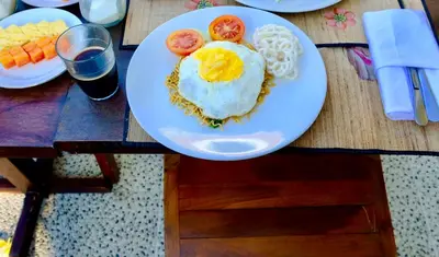 a plate with an egg and tomatoes on a table at Kubu Green in Nusa Dua