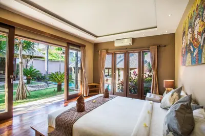 a bedroom with a large bed and large windows at Rachline Villa in Kerobokan