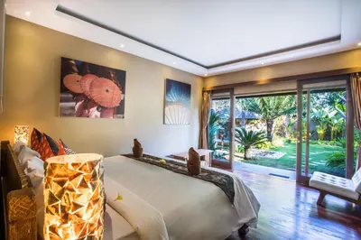 a bedroom with a large bed and a large window at Rachline Villa in Kerobokan