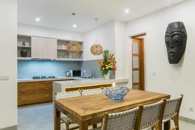 a kitchen and dining room with a wooden table and chairs at Villa Kobe Beachside Berawa Canggu location in Canggu