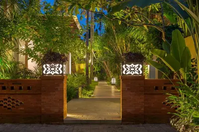 a walkway through a garden with trees and plants at Alaya Dedaun Kuta in Legian