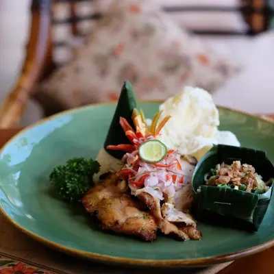 a plate of food with meat and vegetables on a table at Alaya Dedaun Kuta in Legian