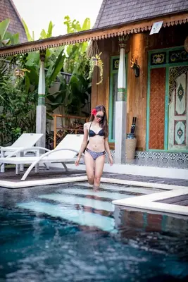 a woman in a bikini standing in a swimming pool at Kubu Kayu Villas in Seminyak