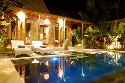 a house with a swimming pool at night at Kubu Kayu Villas in Seminyak