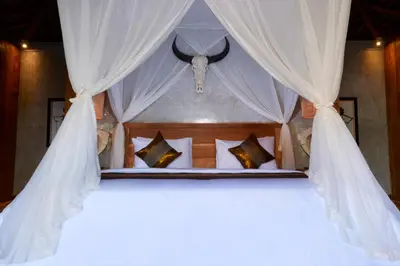 a bedroom with a bed with white drapes at Kubu Kayu Villas in Seminyak