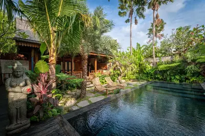 a garden with a pool in front of a house at Kubu Kayu Villas in Seminyak