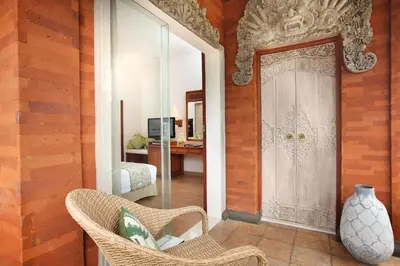 a room with a door and two chairs and a vase at Bali Mandira Beach Resort & Spa in Legian
