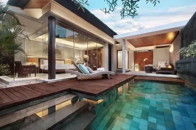 a villa with a swimming pool and a house at Bali Mandira Beach Resort & Spa in Legian