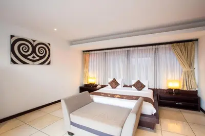 a bedroom with a bed and a couch and a window at Jay's Villa Umalas in Canggu