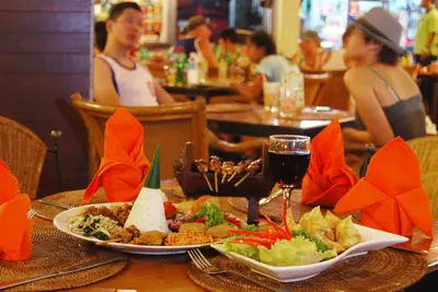a table with plates of food and a glass of wine at Yulia Beach Inn Kuta in Kuta