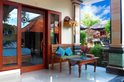 a room with a glass door with a bench and a table at CR Tris Rooms Seminyak in Seminyak