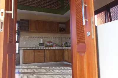 an open door to a kitchen with wooden cabinets at CR Tris Rooms Seminyak in Seminyak