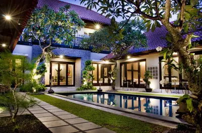 a villa with a swimming pool at night at Sindhu Mertha Suite in Sanur