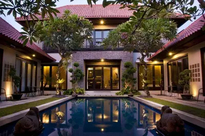 a villa with a swimming pool in front of a house at Sindhu Mertha Suite in Sanur