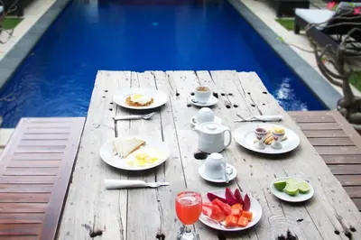 a wooden table with plates of food and fruit on it at Sindhu Mertha Suite in Sanur