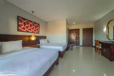 a hotel room with two beds and a mirror at Nirmala Hotel Jimbaran in Jimbaran