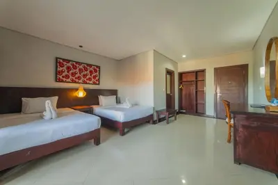 a hotel room with two beds and a desk at Nirmala Hotel Jimbaran in Jimbaran