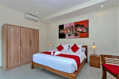 a bedroom with a large white bed with red pillows at Rumah Indah Villa in Seminyak