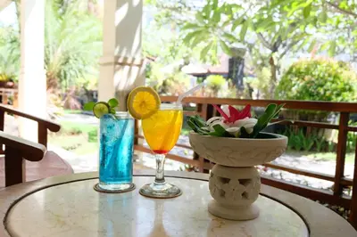 a table with two cocktails and a bowl of flowers at Kuta Beach Club Hotel in Kuta