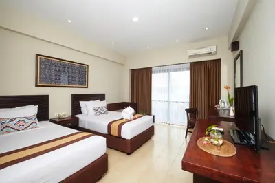 a hotel room with two beds and a table at Grand Santhi Hotel in Denpasar