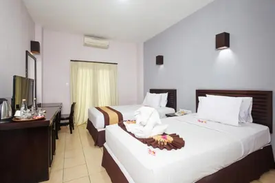 a hotel room with two beds and a television at Grand Santhi Hotel in Denpasar