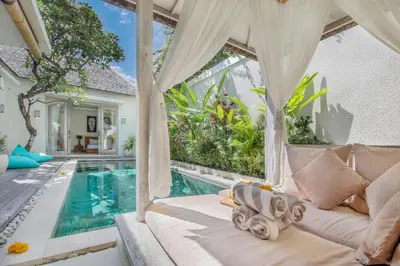 a living room with a white couch next to a swimming pool at Villa Safari in Seminyak